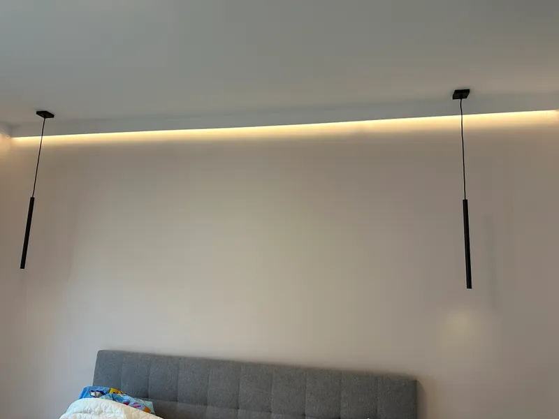 Rejtett LED-szalag a mennyezeti vályúban, két fekete függeszték lámpatesttel