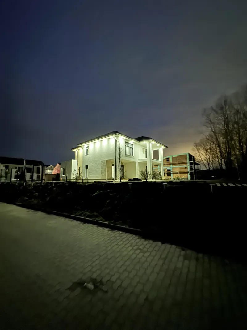 Esti családi ház homlokzata világító ereszalatti kültéri lámpasorral